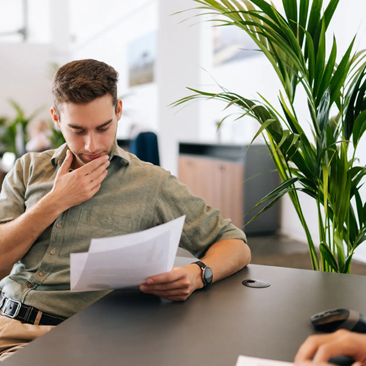 Man reading through paperwork at an office desk